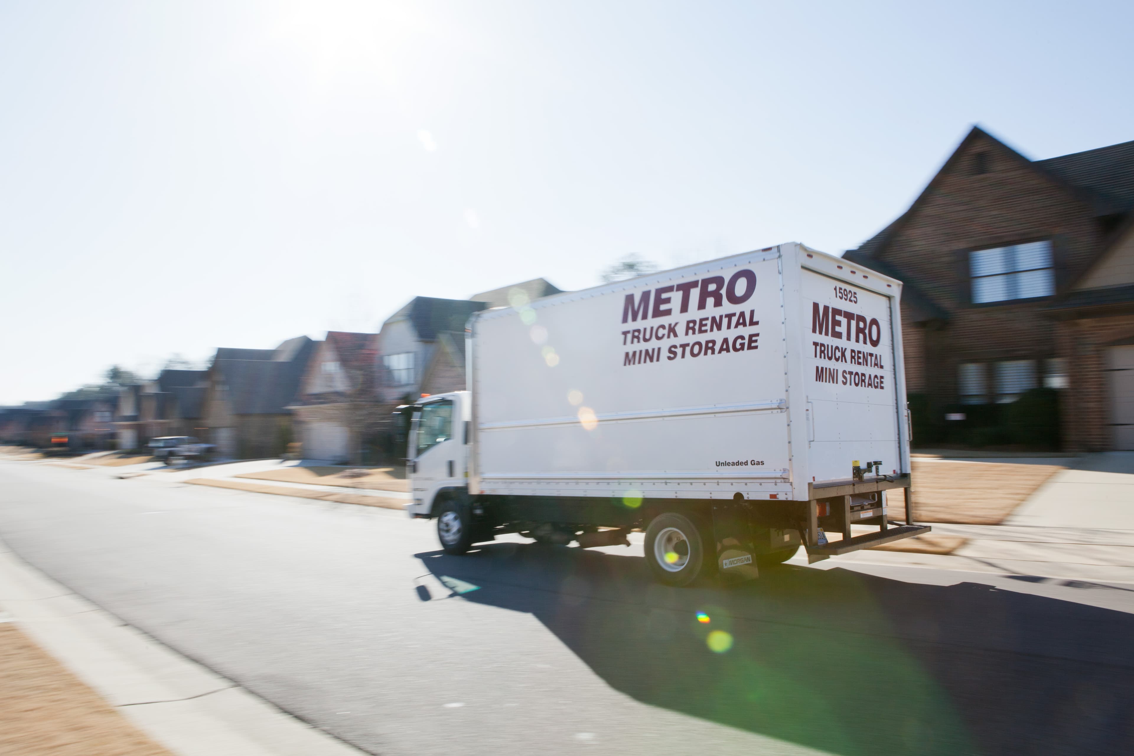 Metro truck driving through a suburban neighborhood.