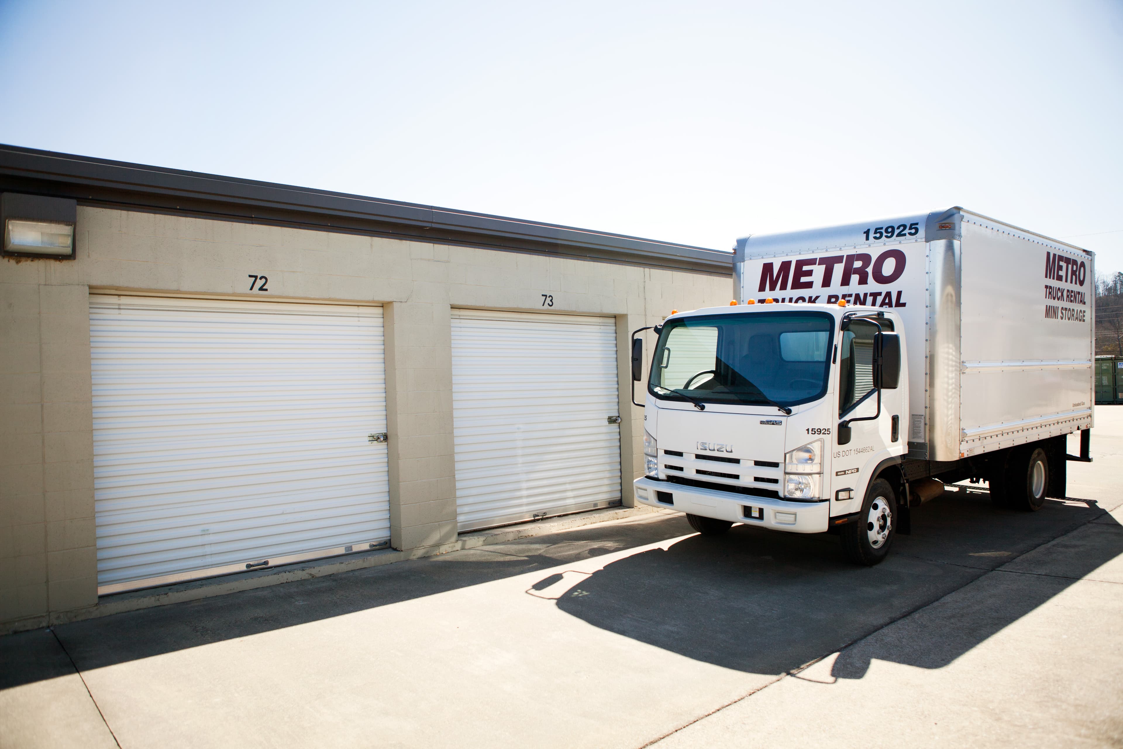Metro moving truck parked beside self-storage units.